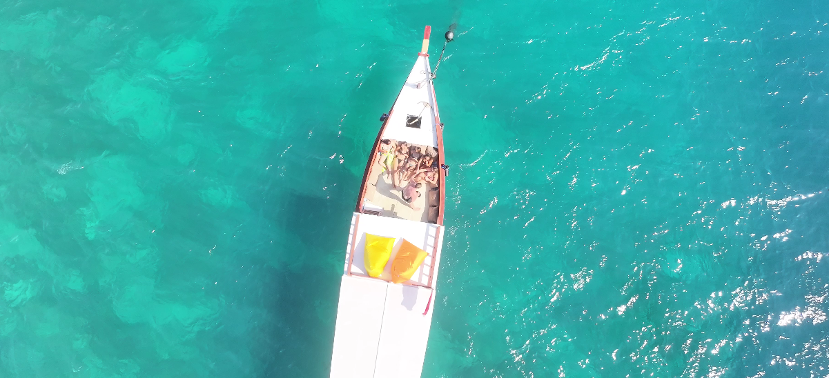 Top-down aerial view of the Jasper boat with guests relaxing on deck in turquoise water